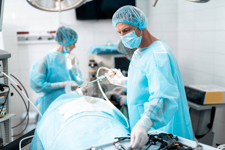 现代手术室中戴着防护面罩的中年医生的腰部肖像背景图片