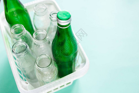 不同的玻璃瓶废物准备回收在绿色背景上的白色篮子社会责任生态关怀图片