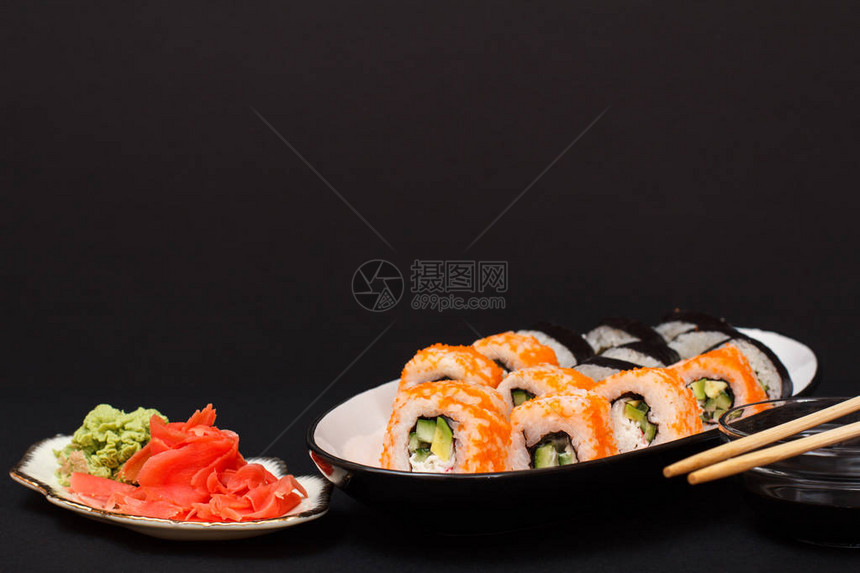 寿司卷配紫菜米饭鳄梨片黄瓜陶瓷盘上的飞鱼子板配红腌姜和芥末碗用酱油和木图片