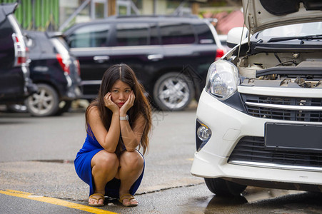 年轻绝望和忧心忡的亚洲日本女因汽车发动机故障而困在路边图片