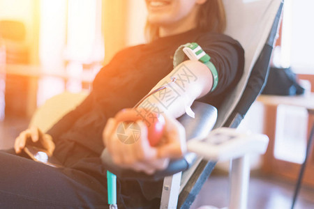 作为献血的年轻女子捐血时手握图片