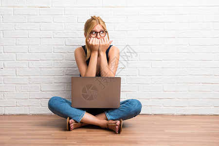 金发女孩拿着笔记本电脑坐在地上图片