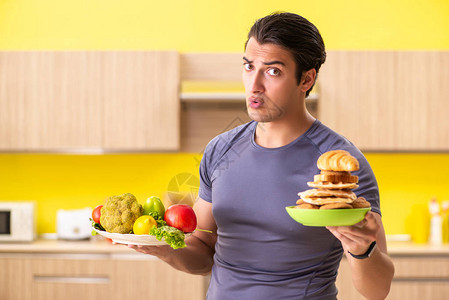 男人在健康食品和不健康食品之间图片