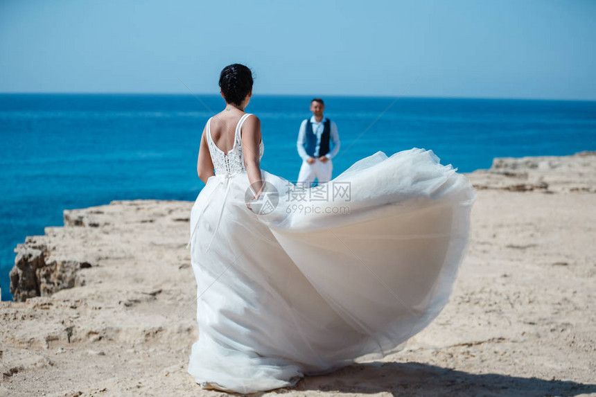 美丽微笑的年轻新娘和新郎走在沙滩上图片