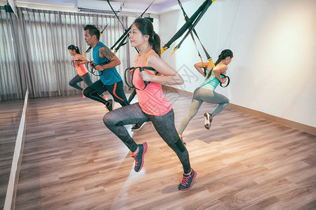 年轻的亚洲人用所有的身体力量做弹力绳练习运动量来找到房间拉图片