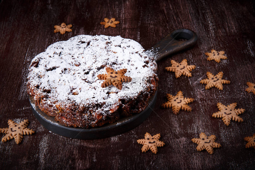 传统的圣诞蛋糕面包饼和姜饼干以黑木桌上的雪图片