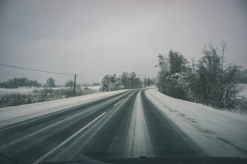 冬季乡下雪和冰覆盖的公路带轮胎轨迹图片