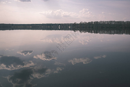 水的自然体在平静的水面上沉积着树木和云层图片