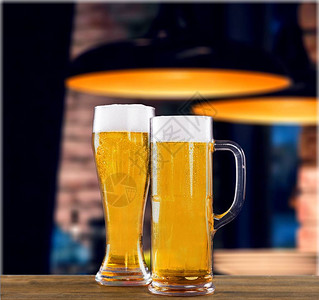 木桌上玻璃杯里的冰镇啤酒图片
