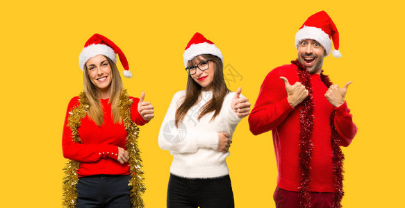 一群为圣诞节日打扮的金发女人在黄色上举起大拇指手势图片