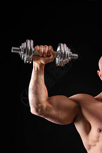 深色背景中带哑铃的肌肉健美运动员图片
