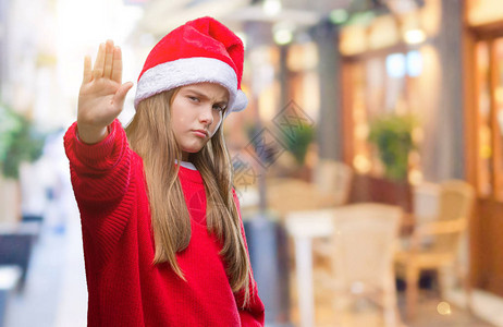 年轻漂亮的女孩戴着圣诞帽在孤立的背景下停止用手掌脸上带着消极和严肃的图片
