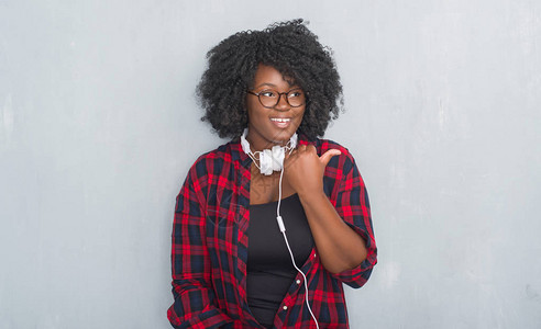 年轻的非洲裔美国女人在灰色的垃圾墙上戴着耳机图片