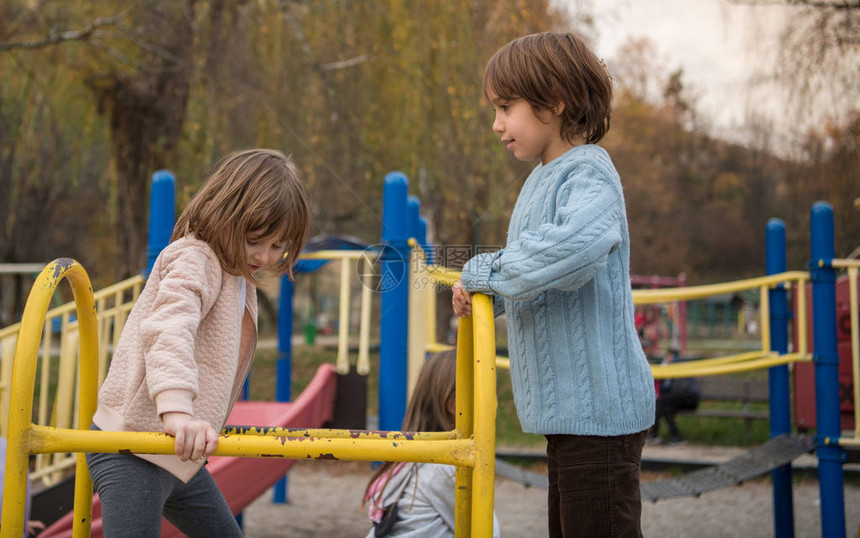 可爱的小女孩和男孩在儿童公园里玩得开心图片