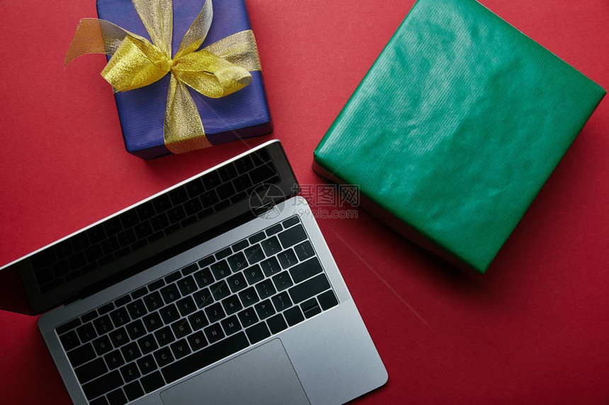 用笔记本电脑键盘在红色背景上贴着包装礼物的红背面剪裁式笔图片
