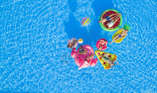 适合女孩和肌肉发达的男孩躺在泳池中的彩色漂浮物上图片