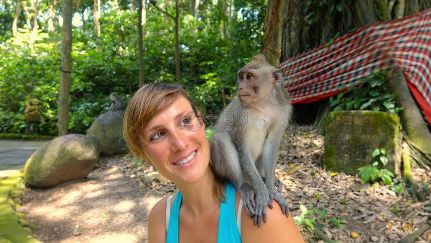 年轻的白种人旅行者看着她肩上的小猕猴图片