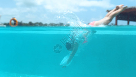 活跃的年轻女子潜入壮观的空游泳池并溅起玻璃水图片