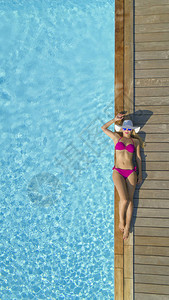 快乐的女游客在令人惊叹的蓝色豪华游泳池附近放松图片