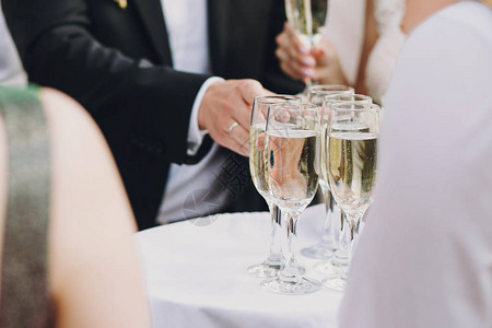 服务员在户外的婚礼招待会为客人提供盛装香槟杯的餐具图片