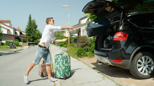 住在阳光明媚的郊区的白人男在令人敬畏的暑假前收拾行李图片