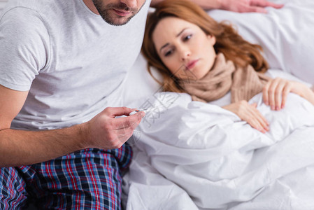丈夫检查生病妻子体温并在卧室拿着温度图片