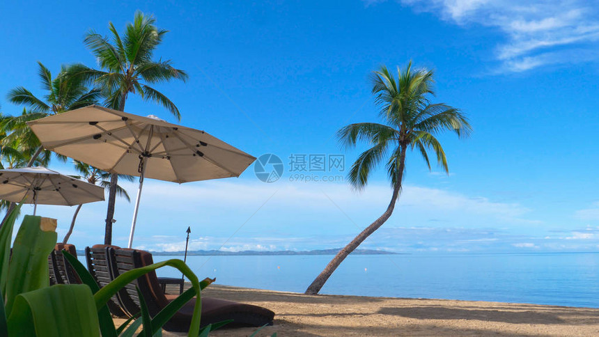 美丽的豪华酒店躺椅在库克群岛令人叹为观止的热带海滩的遮阳伞下休息图片