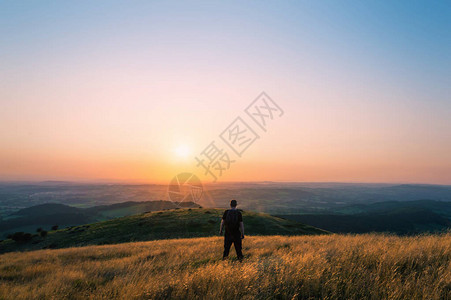 一个山丘上的徒步者看着整个英国风景朝日落的高清图片