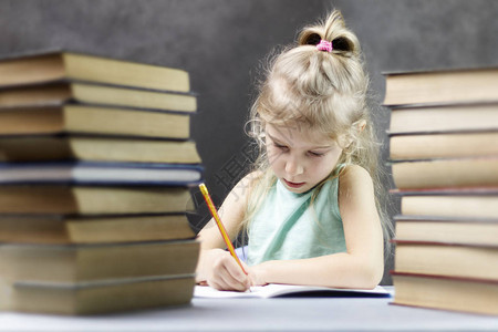女学生金发女孩一叠书和铅笔写在笔记本图片