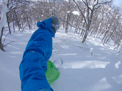 酷的滑雪者雕刻新鲜的粉雪并避开雪山上的树木图片