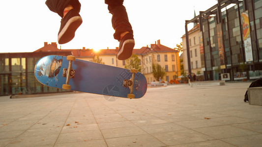 蓝色滑板在年轻而运动的滑板手脚下翻转图片