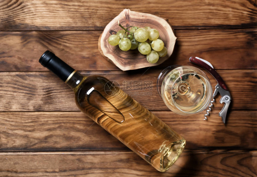 木制背景上的瓶和杯白葡萄酒图片