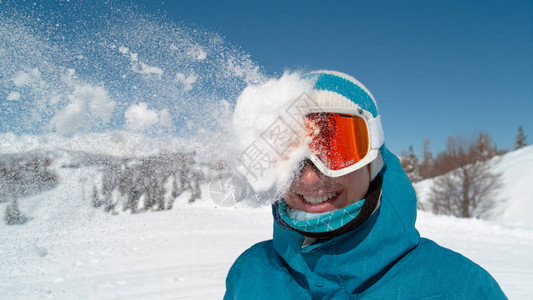 戴着橙色滑雪护目镜的兴奋的白人女孩被雪球击中头部图片