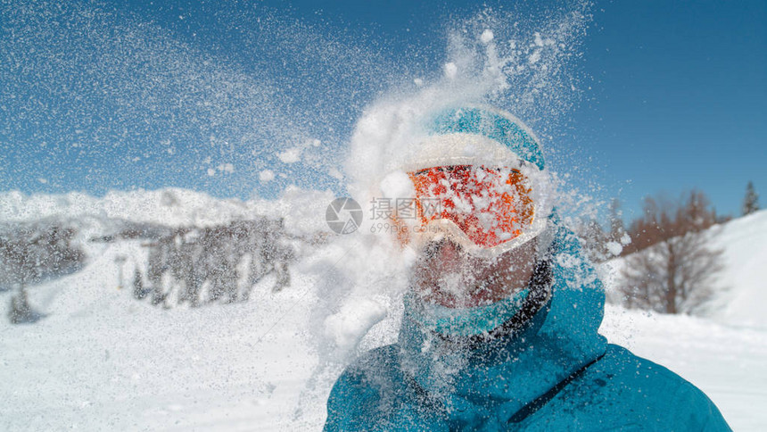 戴着滑雪护目镜的微笑女孩被一个大雪球击中头部图片