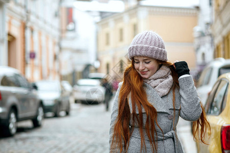 穿着冬帽和大衣在城市漫步的红发美图片