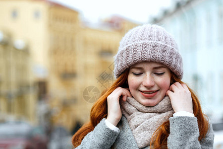 穿着织的温暖毛帽和围巾在街上摆着围巾的漂亮红发女图片
