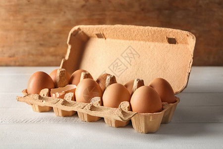 白桌上纸箱中的碎鸡蛋和全鸡蛋图片