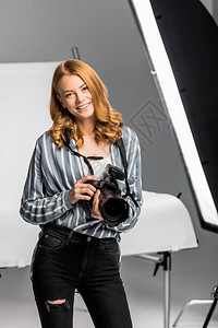 美丽的年轻女摄影记者在摄影工作室的镜图片