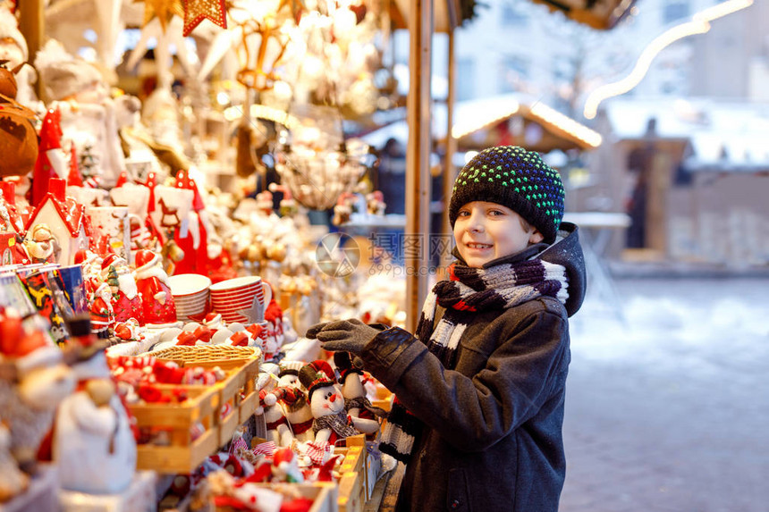 可爱的小男孩在圣诞市场上选择装饰漂亮的孩子为树购买玩具和装饰品德图片