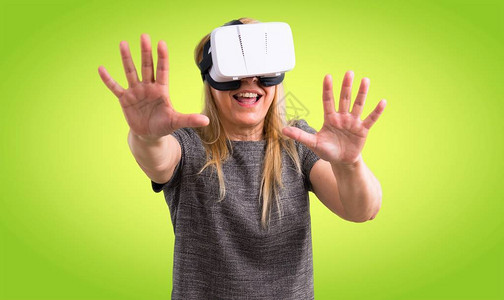 使用VR眼镜的中年金发女子关于丰富多彩背景的背景图片