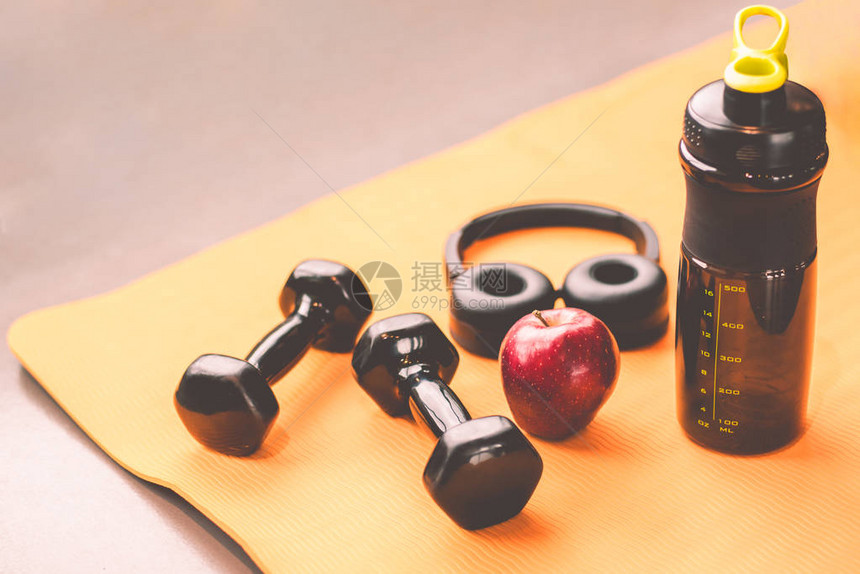 在健身房健身运动训练中心用哑铃锻炼健身器材耳机苹果水和蛋白质奶昔瓶健康和生活方式放松健美和饮食图片