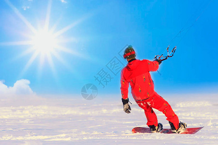 Kite冲浪者骑在雪板上冰冻湖上的雪下图片