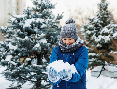 穿着红色帽子蓝色夹克的可爱小男孩拿着和玩雪图片