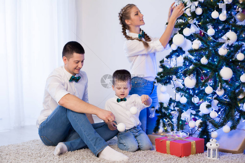 妈和儿子装饰圣诞树礼物新的一年树冬图片