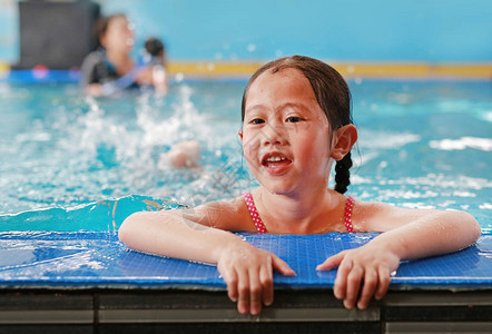 快乐的亚洲小女孩在游泳池里学游泳的肖图片