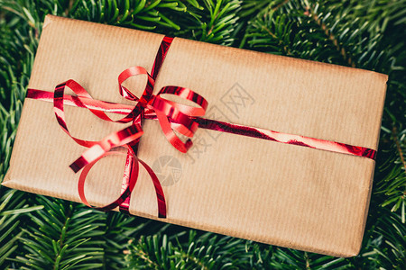 绿色松树或云杉树上的圣诞礼物纸礼品盒上的红丝带有复制空间的图片