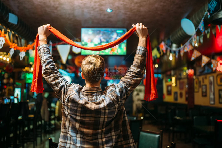 足球迷用围巾举起手来观看体育酒吧最喜爱的球队比赛图片