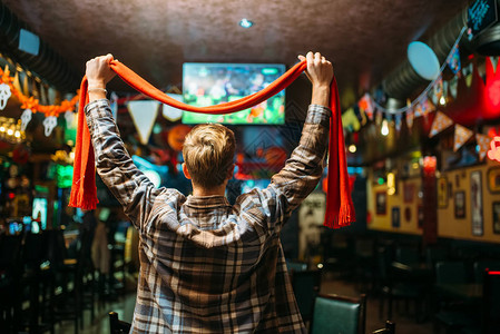 足球迷用围巾举起手来观看体育酒吧最喜爱的球队比赛图片