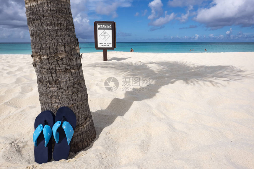 在加勒比海滩上用棕榈树和警告标志进行倾斜图片