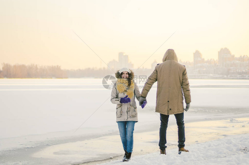主题圣诞假期冬季轻时尚的高加索情侣异恋在结冰的湖岸上行走日期在日落的冬天的情人节爱图片